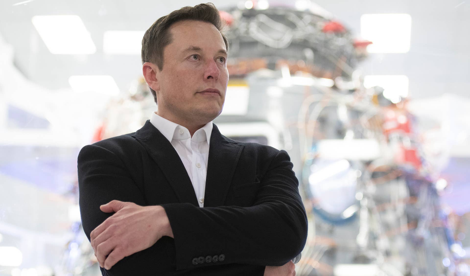 Elon Musk standing with arms crossed