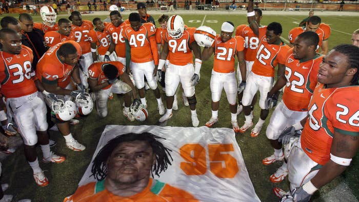 Teammates of Bryan Pata #95 of the University of Miami Hurricanes say a prayer over a mural that was placed at mid-field.