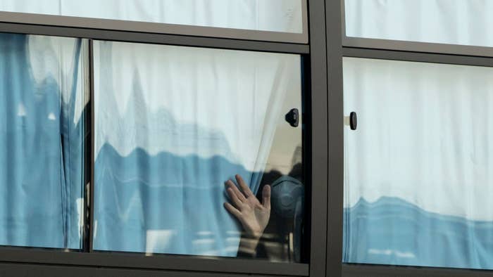 A man waves from a bus carrying passengers who disembarked the quarantined Diamond Princess cruise ship