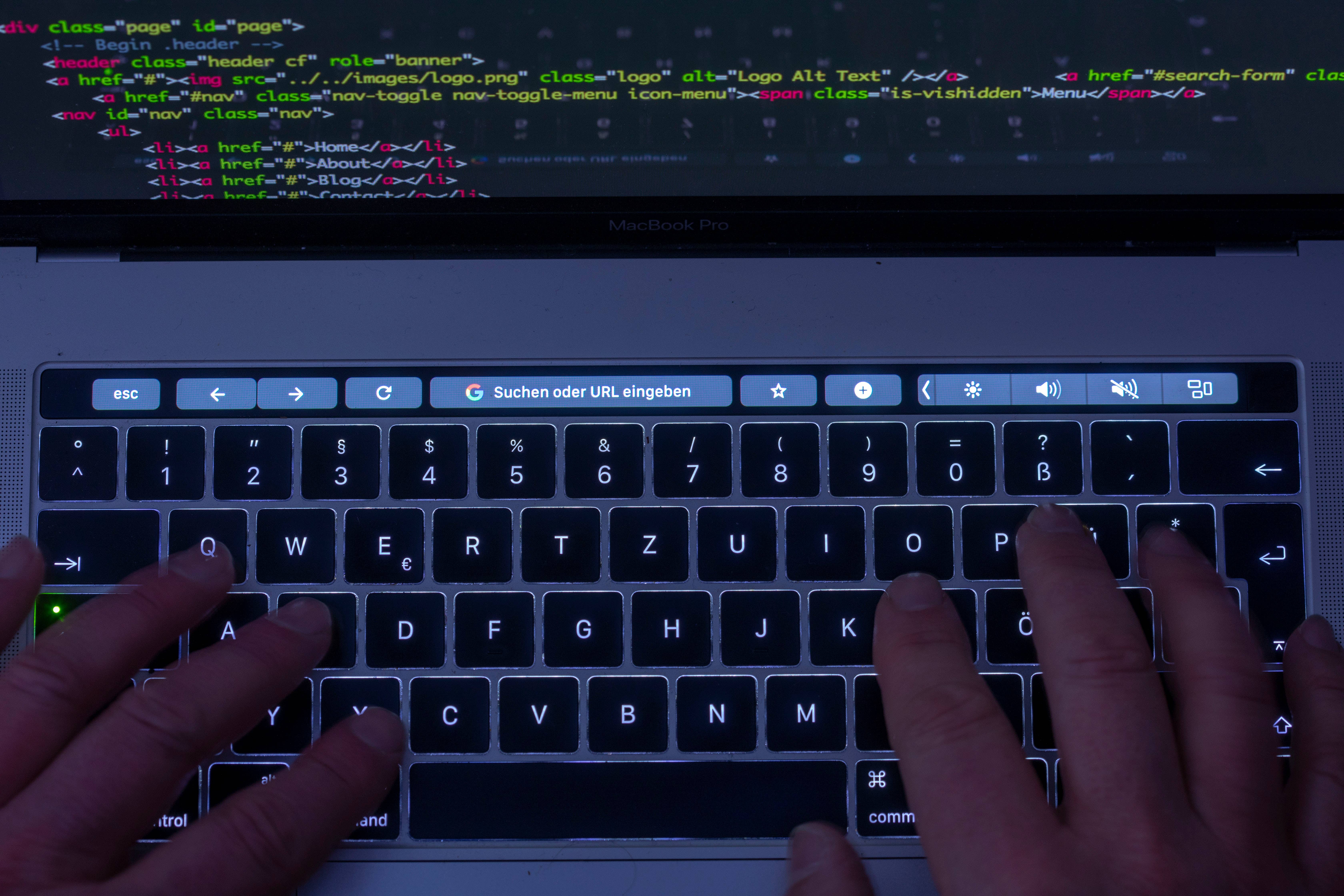 man typing on keyboard with code on screen