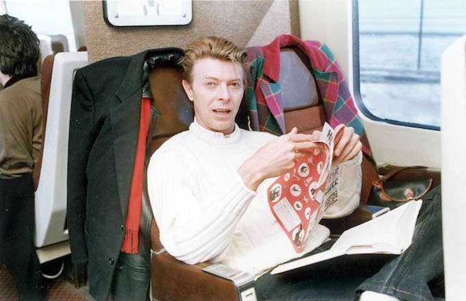 David Bowie circa 1990 reading a comic book on a train.