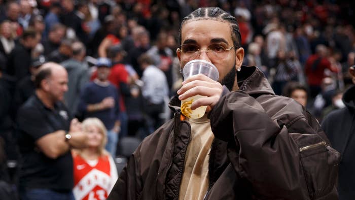 Rapper Drake drinks from a cup as he leaves the court after the first half of Game Six of the Eastern Conference First Round