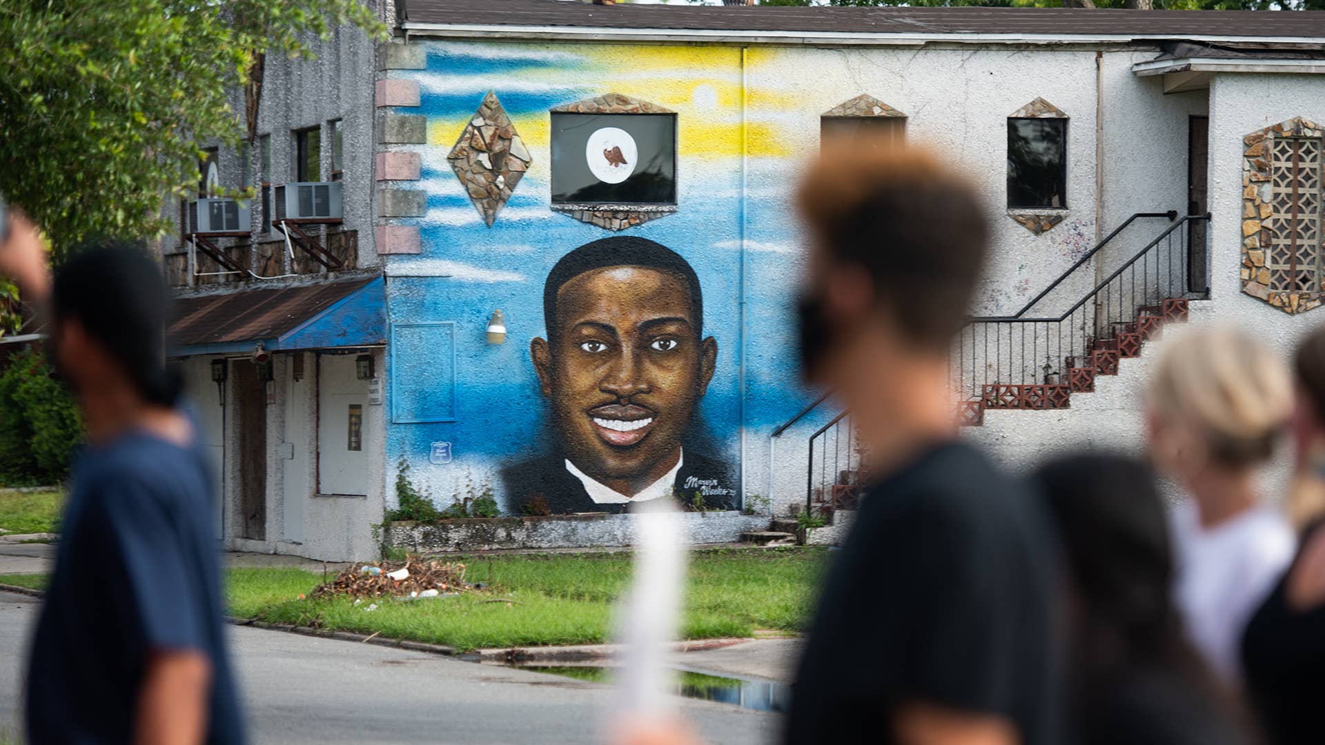 Demonstrators walk past a mural of Ahmaud Arbery in Brunswick, Georgia.