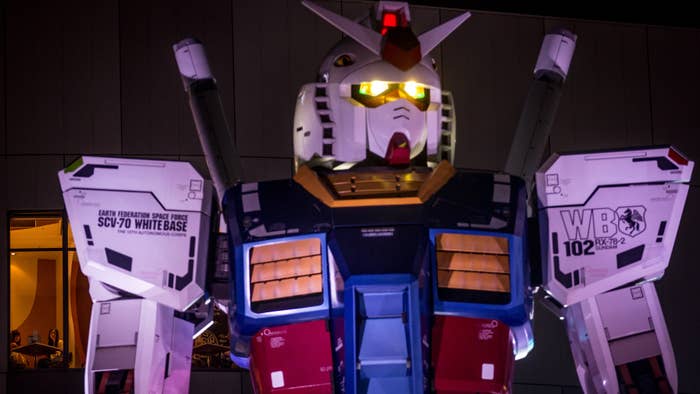 Two women look out from a restaurant window at Gundam.