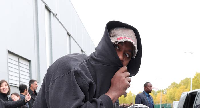 Kanye in a hoodie hiding half his face