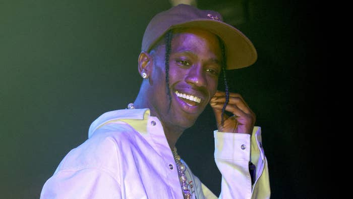 Travis Scott is pictured smiling while on stage