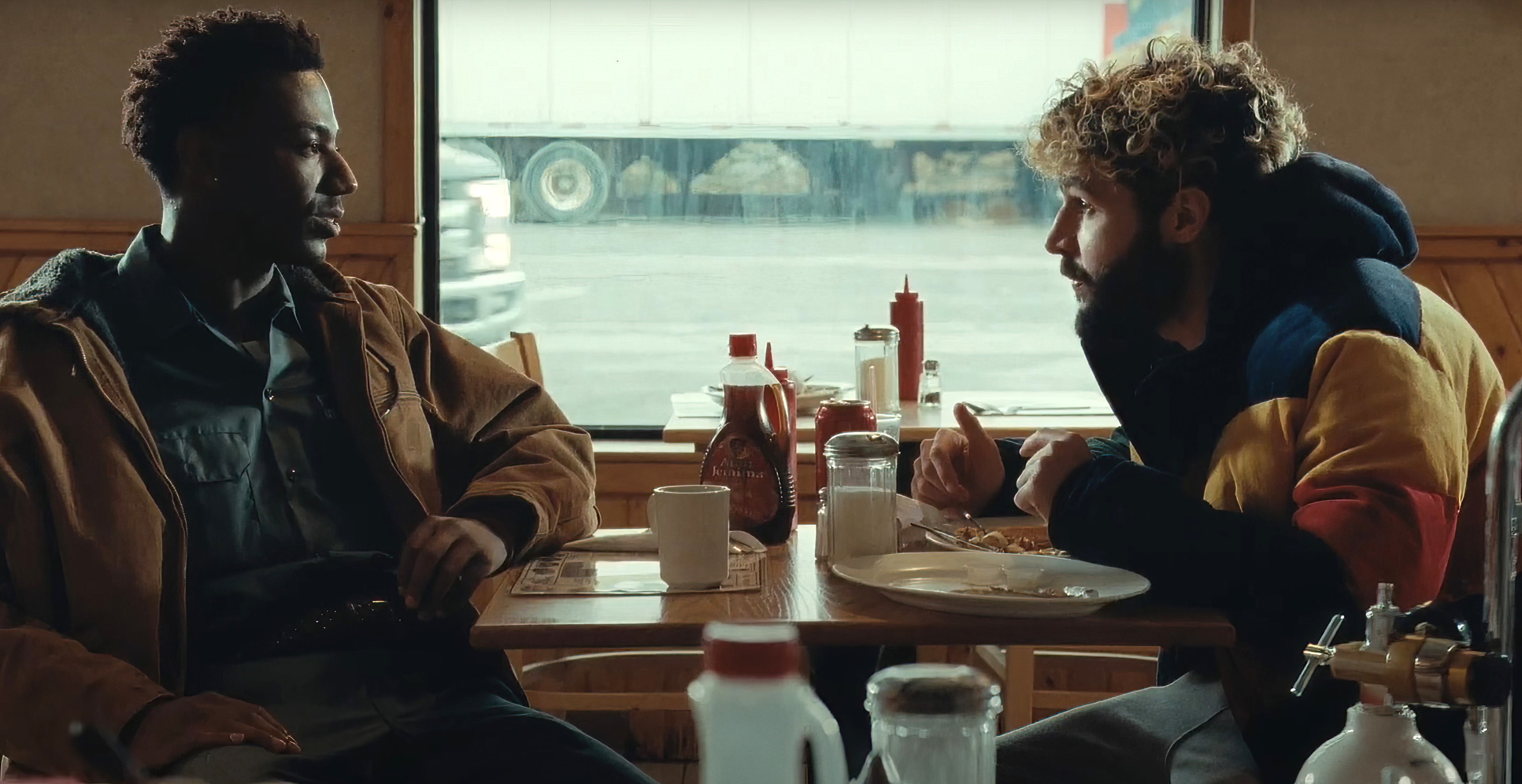 Two friends sit and eat at a diner.