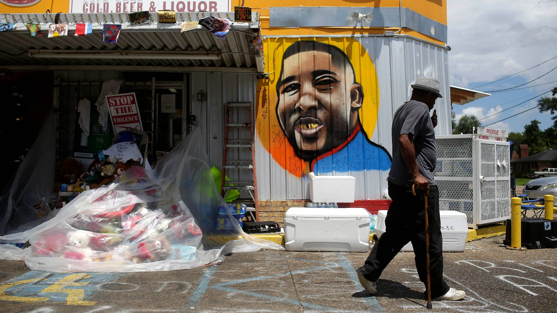 A man walks past a mural of Alton Sterling outside the Triple S Food Mart.