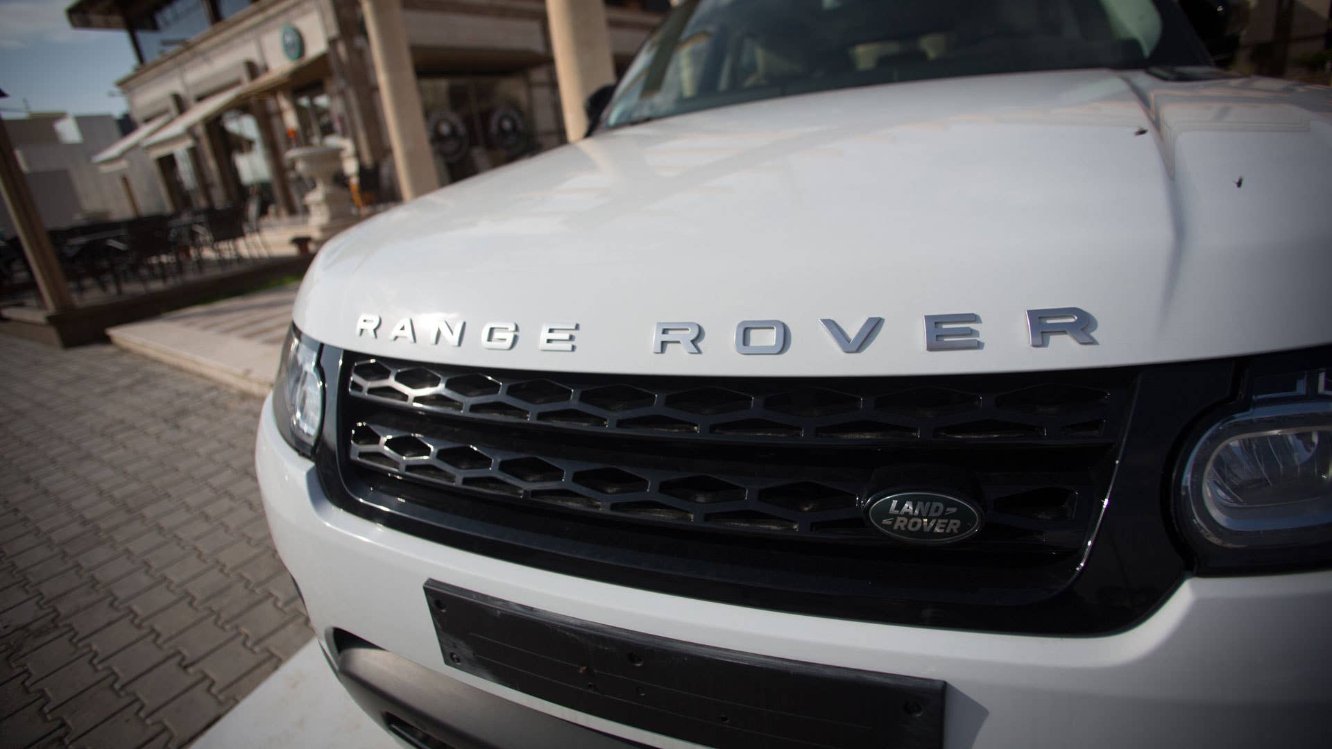 A Range Rover is displayed for sale outside a restaurant complex.