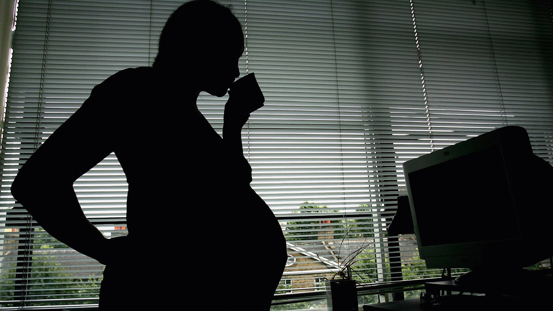 This photo illustration of a pregnant woman is seen stood at the office work station.