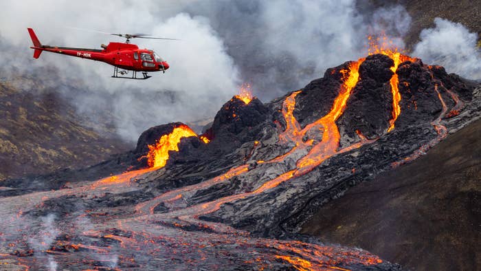 A helicopter flies close to a volcanic eruption