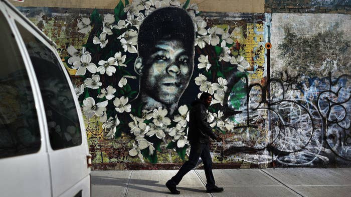 A man walks by a walks by a graffiti memorial in memory of Yusef Hawkins.