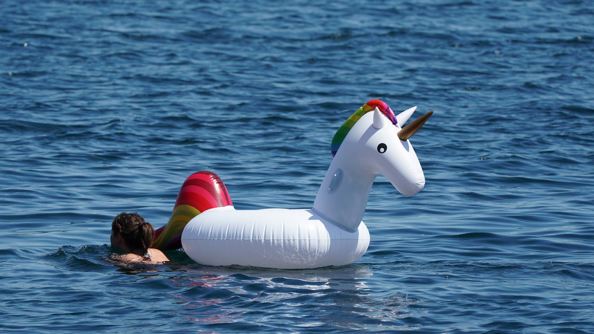 A female swimmer and an inflatable unicorn can be seen.