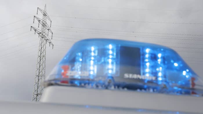 Photo taken of blue light from a police car in front of a power pole.