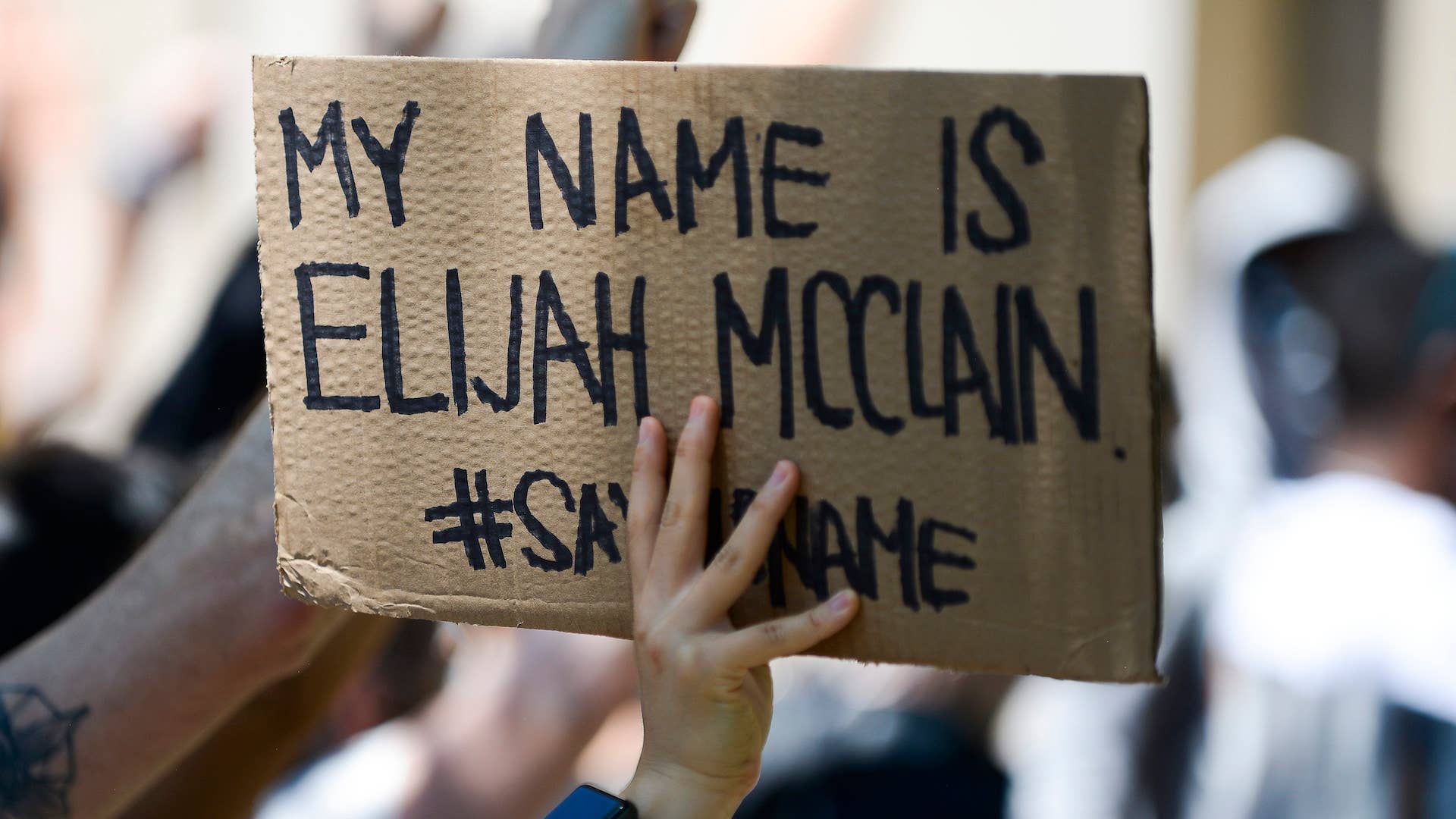 A woman holds sign during rally to demand justice for Elijah McClain.