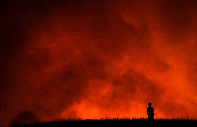 A firefighter watches as a California wildfire rages.