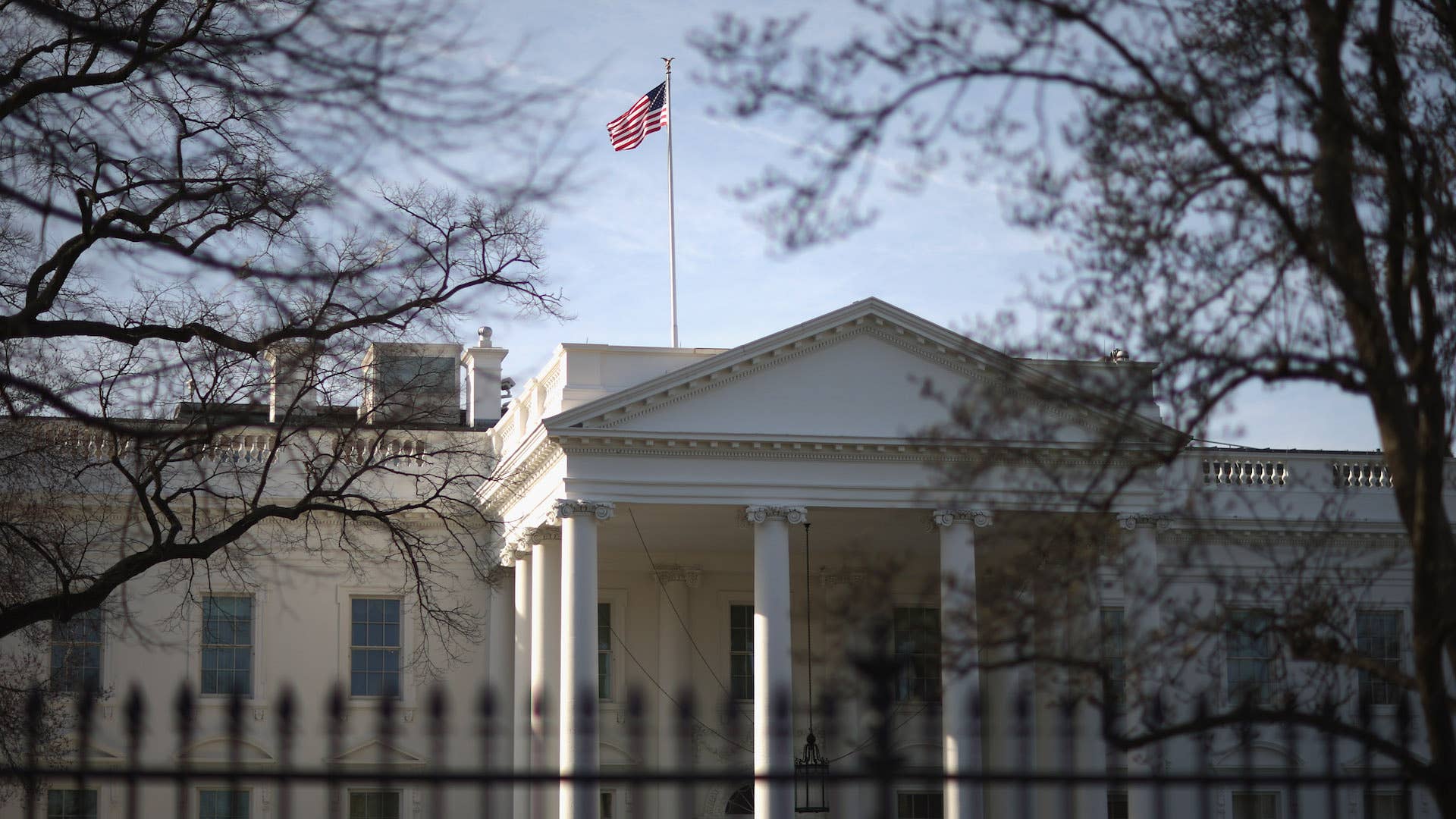 Morning sunlight strikes the flag flying above the White House.