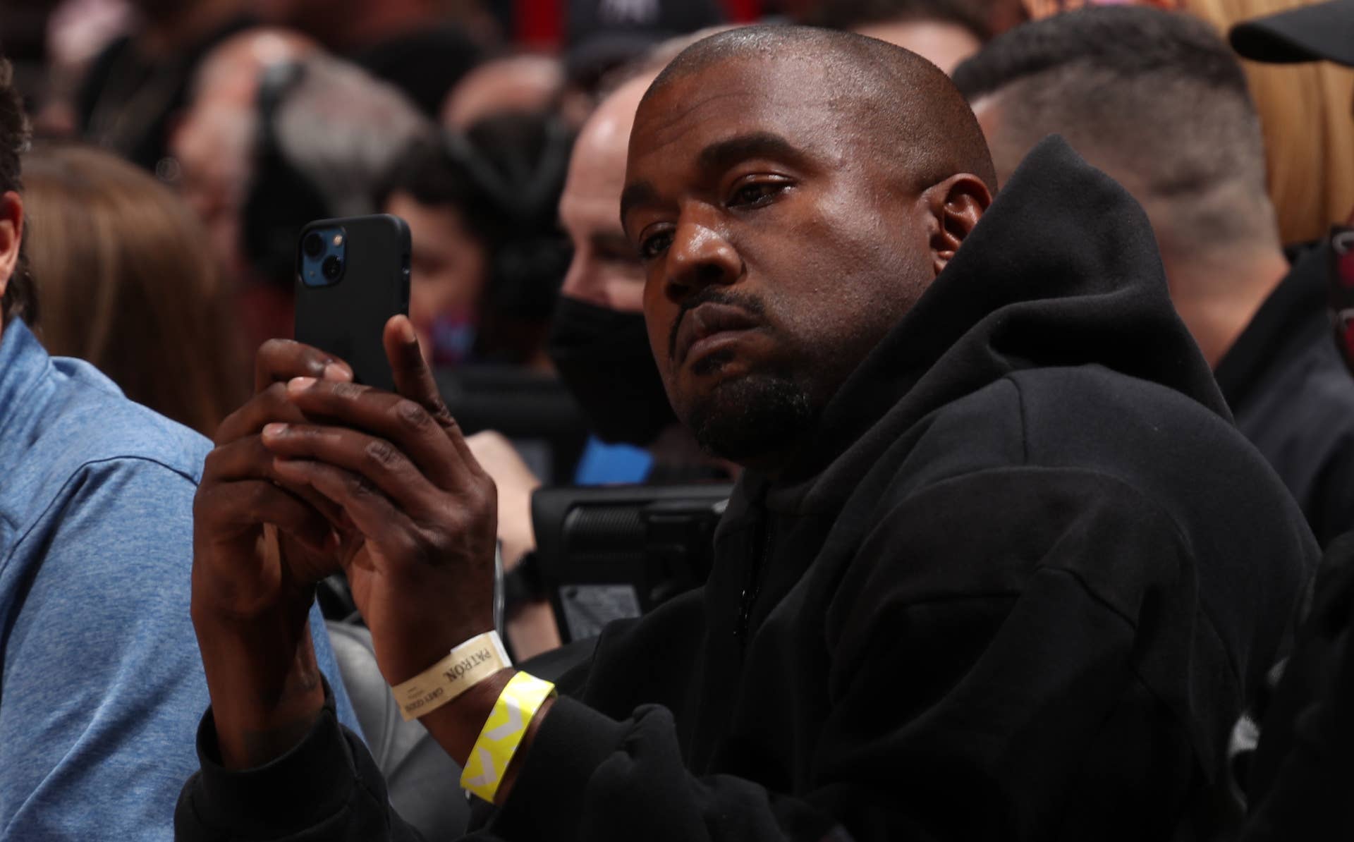 Kanye West looking at a cellular telephone