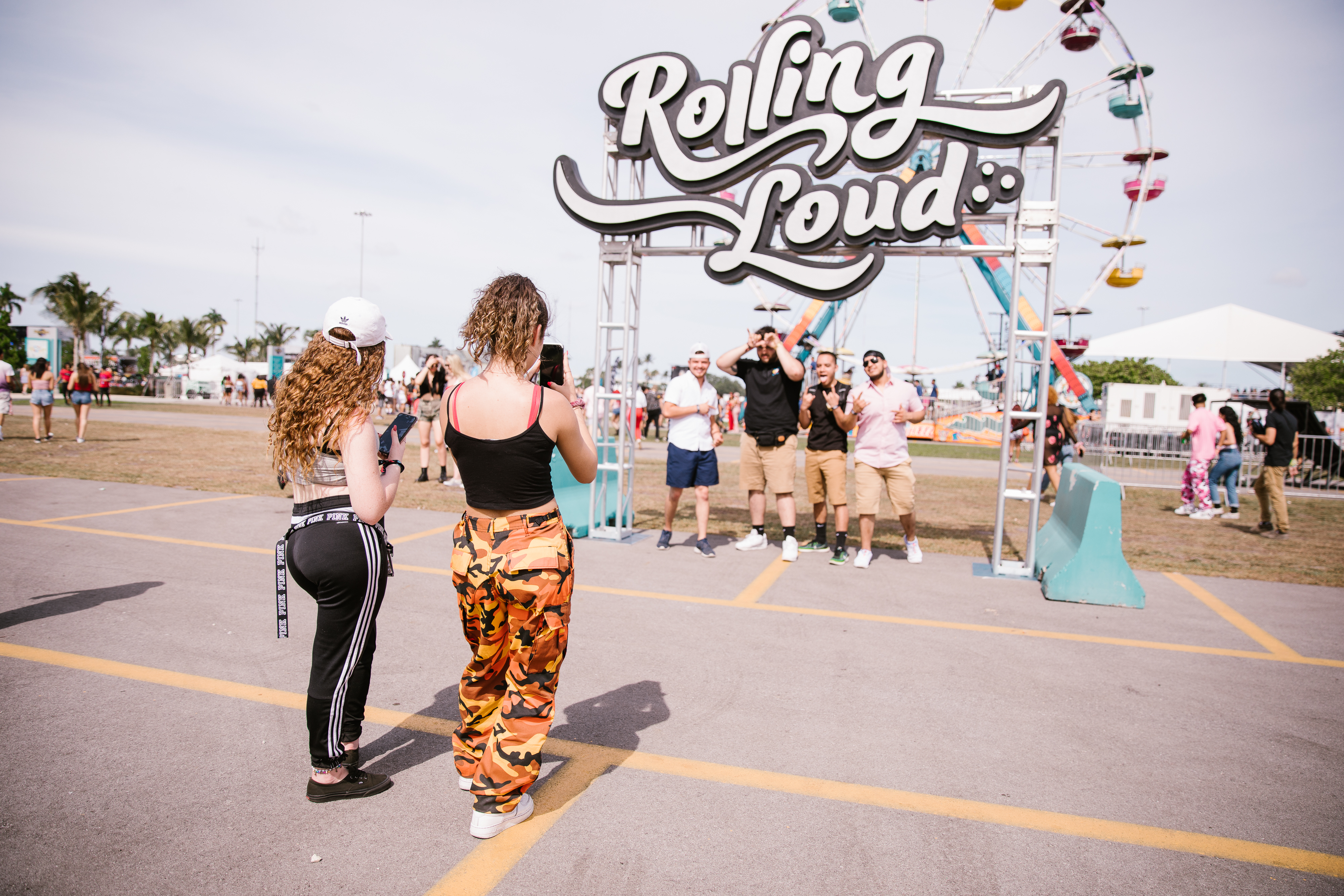 Rolling Loud attendees taking a photo under the festival sign.