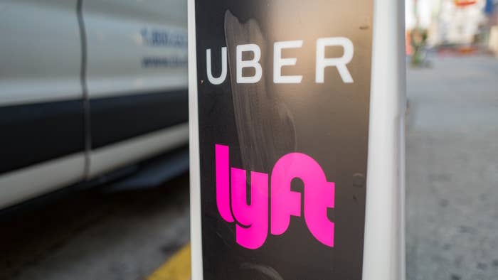 Close up of vertical sign with logos for ridesharing companies Uber and Lyft.