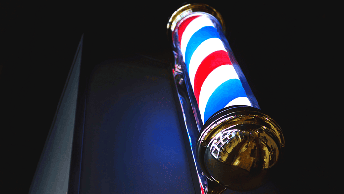 A low angle shot of a barber shop pole at night.