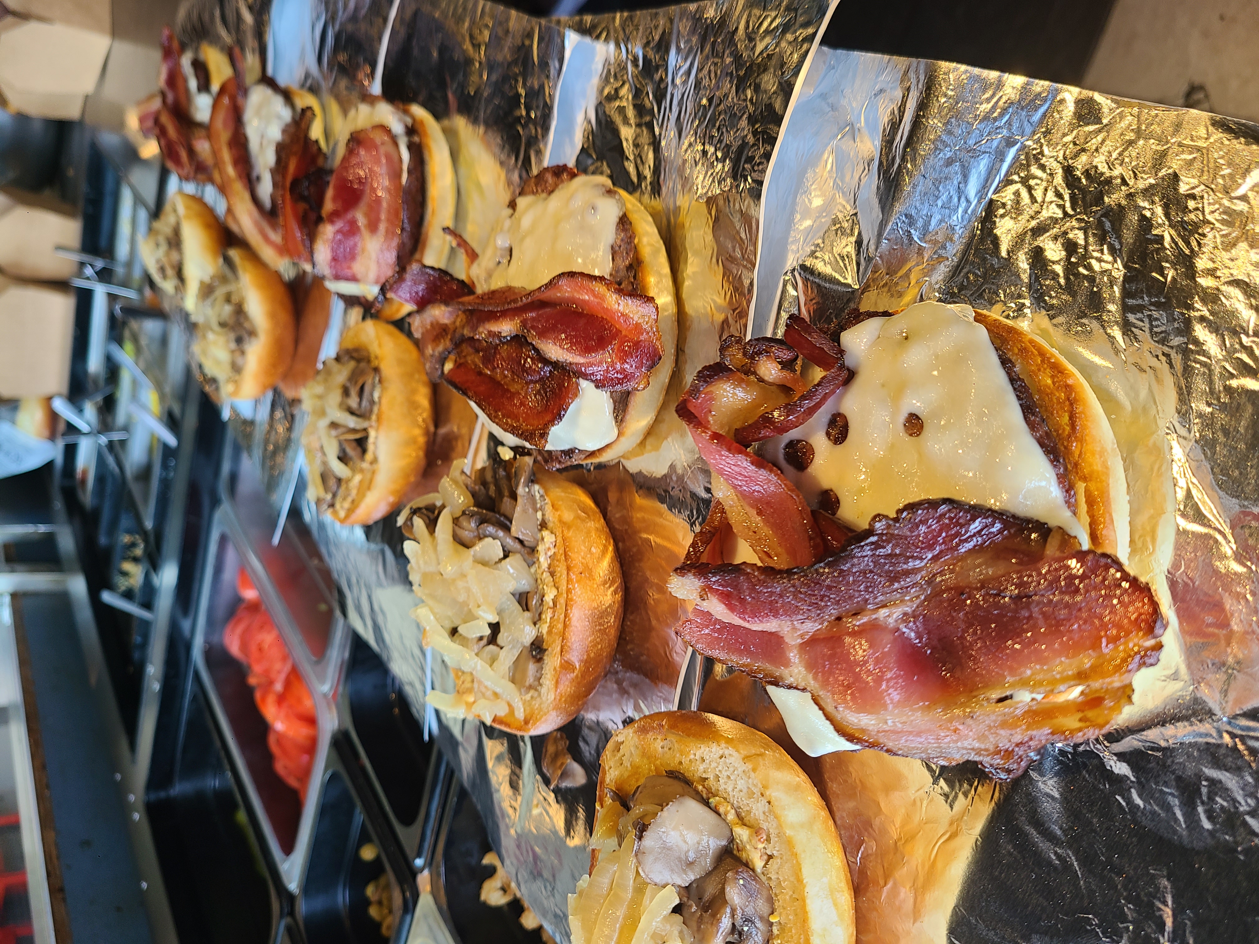 a row of burgers with toppings beside them