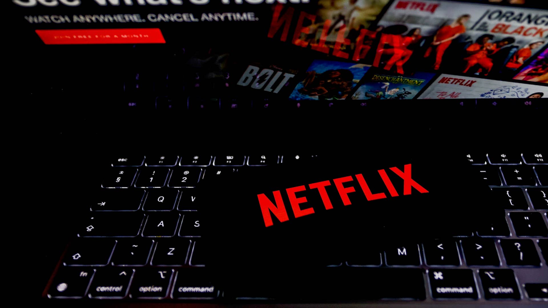 Netflix logo is displayed on a mobile phone screen with Netflix website in a background