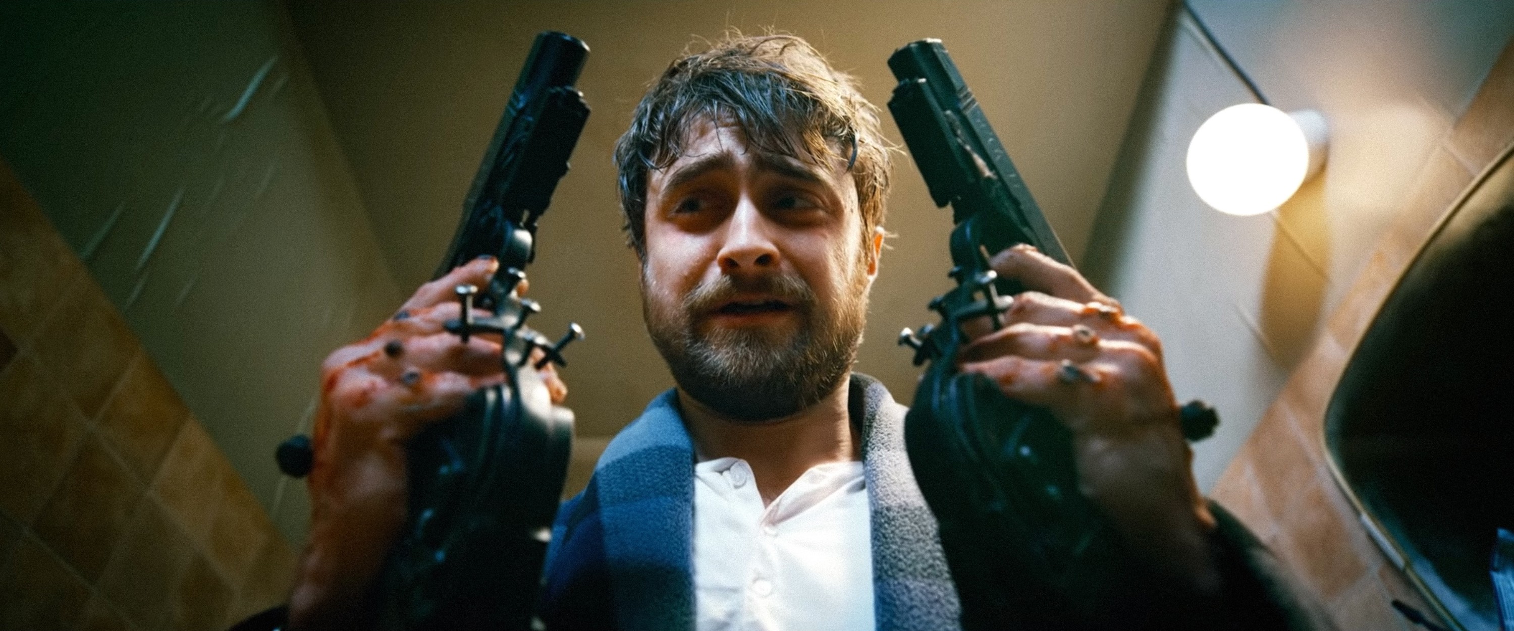 Daneil Radcliffe stares at the two guns he&#x27;s holding.