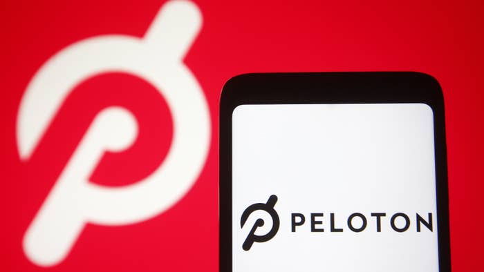 In this photo illustration a Peloton logo is seen on a smartphone and a pc screen.