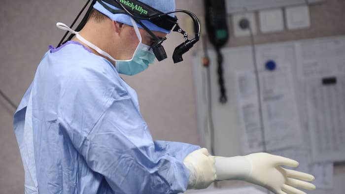 A surgeon puts on gloves before an open-heart surgery