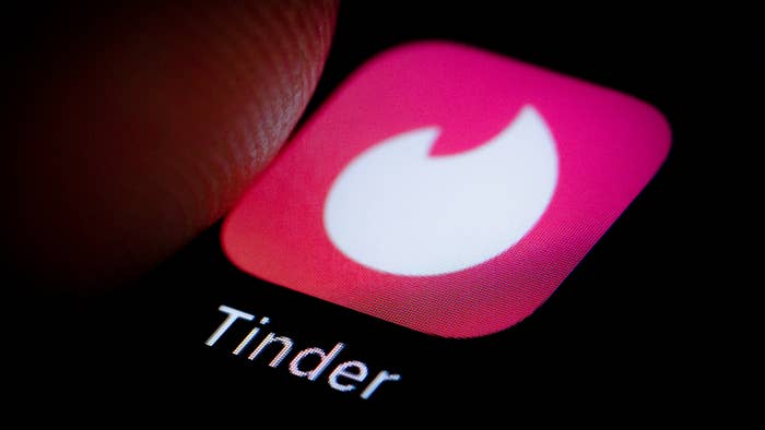 Finger hovers over Tinder app on a smartphone.