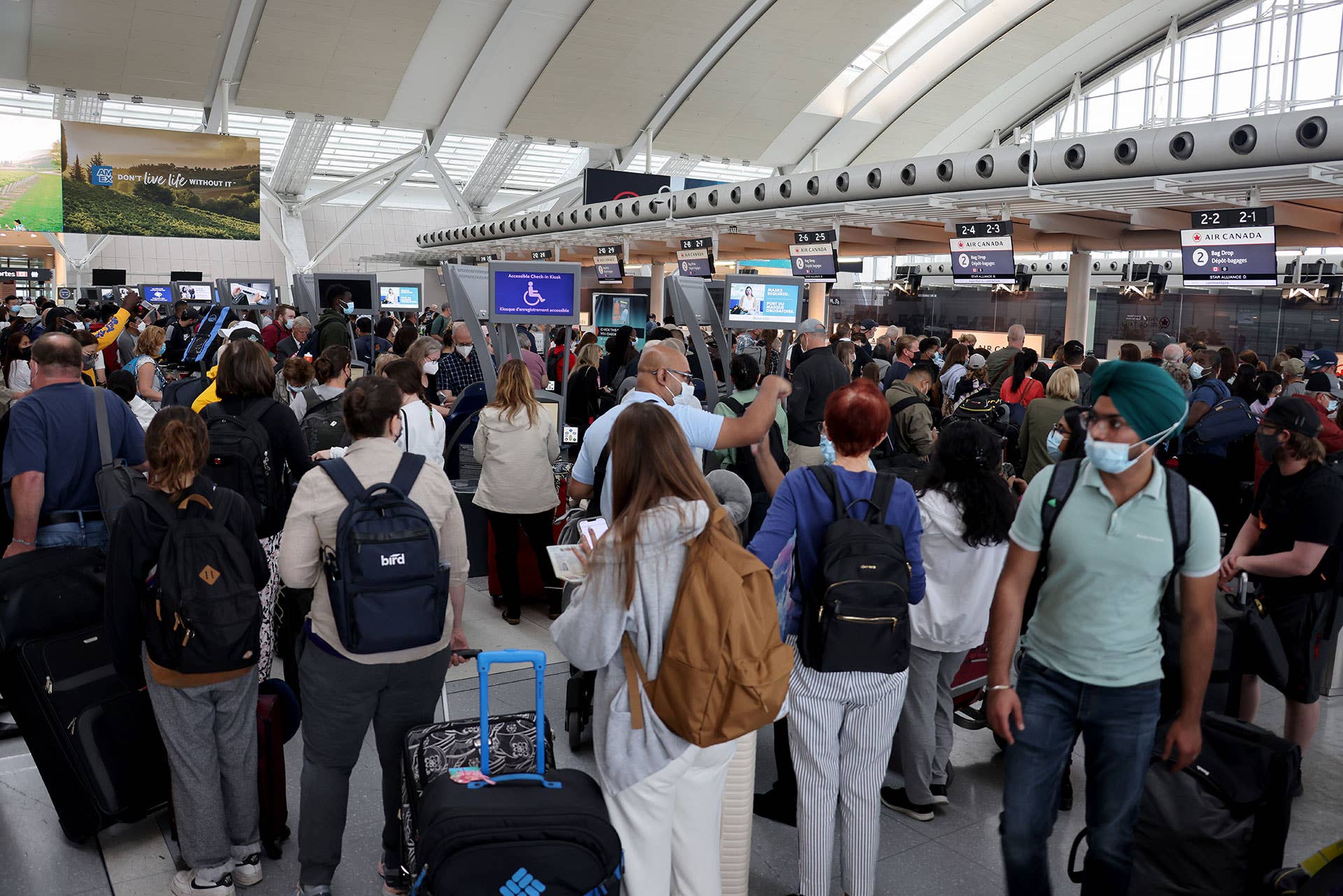 Travelers wearing face masks wait to check-in at Toronto Pearson International Airport on June 30, 2022