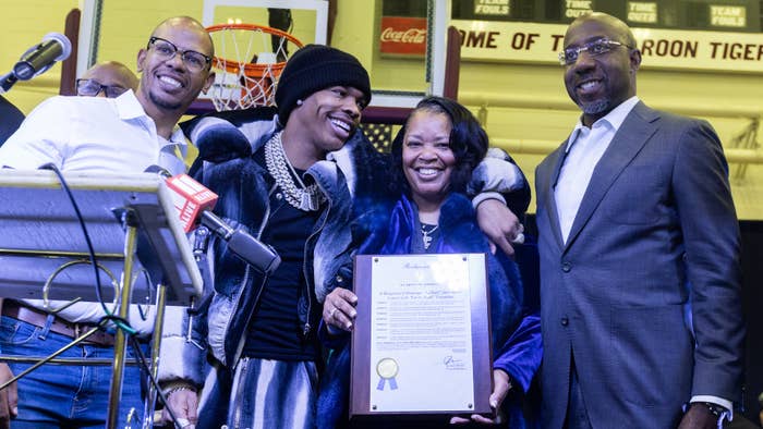 Sen. Raphael Warnock stands on stage as Atlanta City Councilman Jason Dozier recognizes rapper Lil Baby.