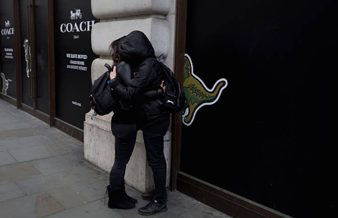A couple wearing black hoodies with faces hidden, hug on Regent Street