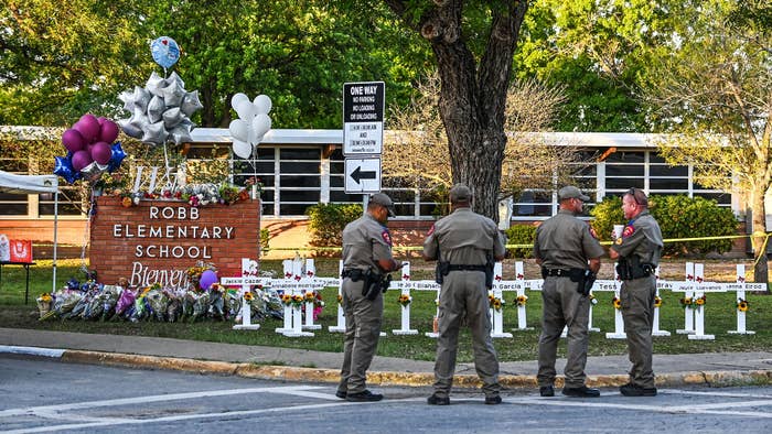 Robb Elementary School and police standing nearby a makeshift memorial