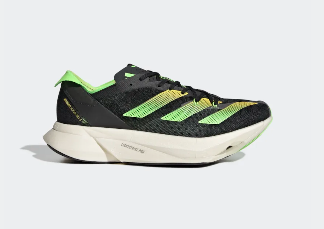 A black Adidas sneaker with green and yellow ombre stripes and a cream sole