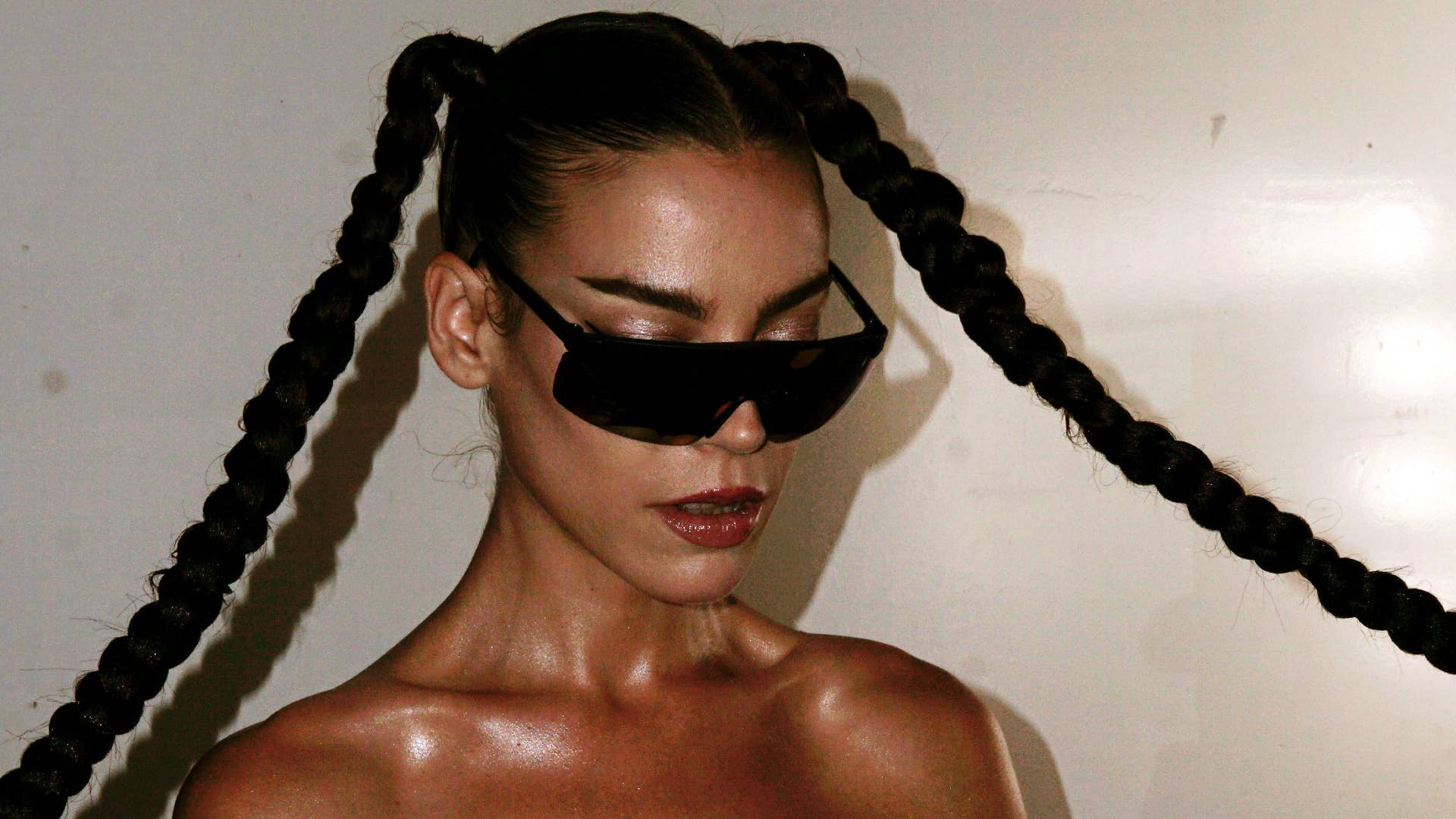 Eva Show wearing thick black sunglasses and two long braids