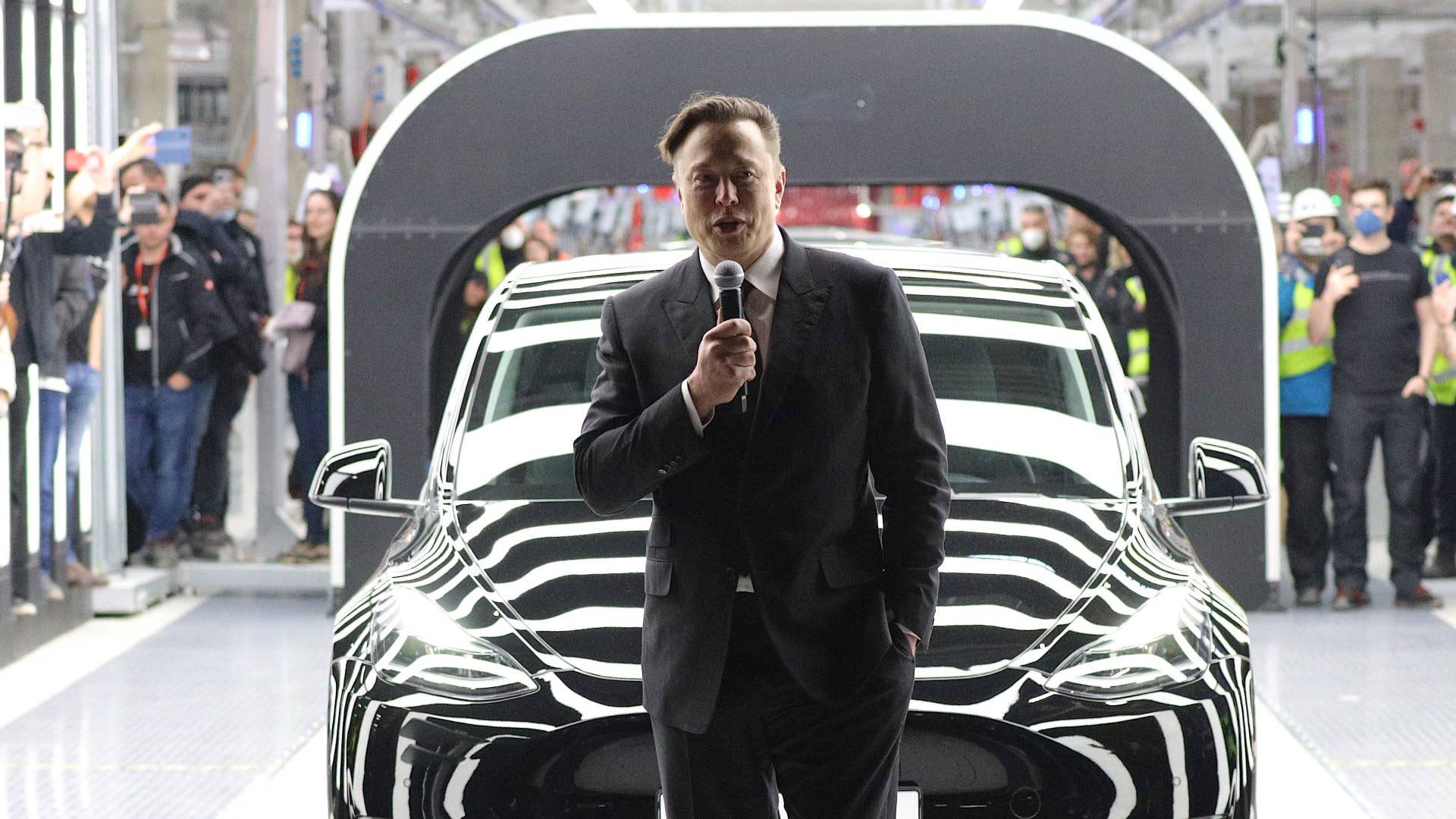 Elon Musk is pictured holding a microphone