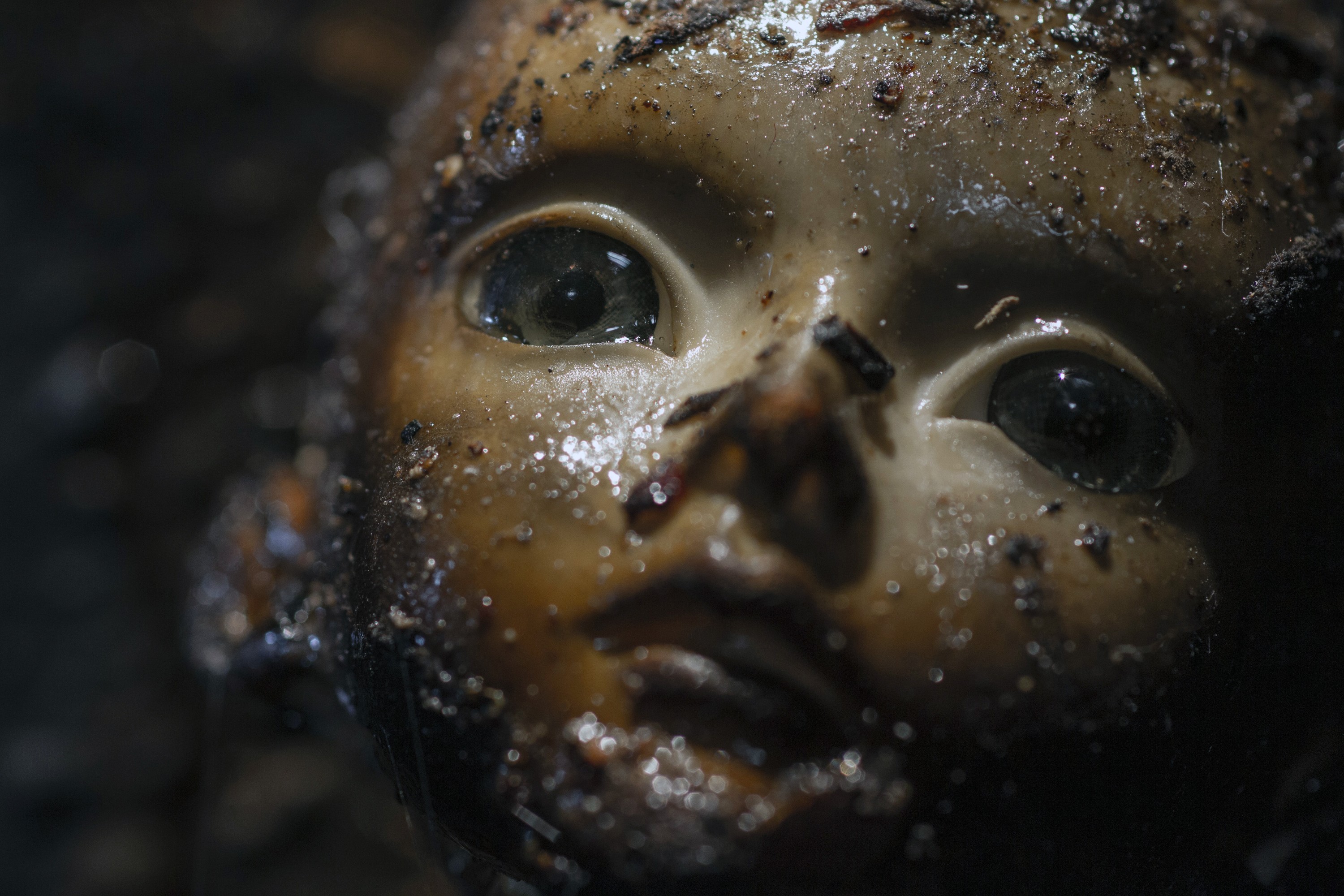 A scary doll with dirt on its face.