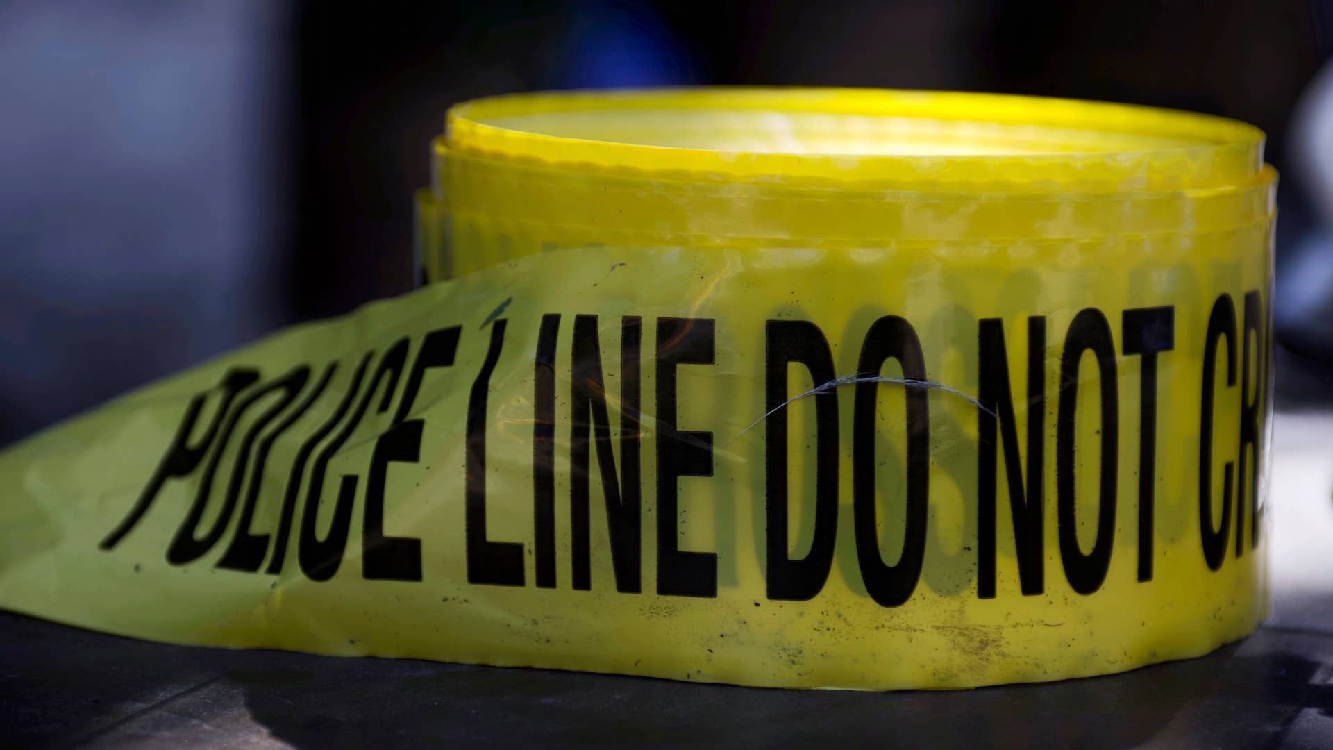 Roll of crime scene tape is unused as police officers interact with youth