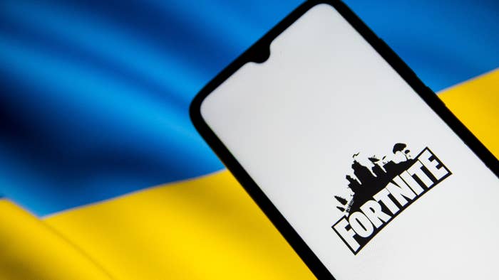 &#x27;Fortnite&#x27; logo on a smartphone screen with Ukraine flag in the background.