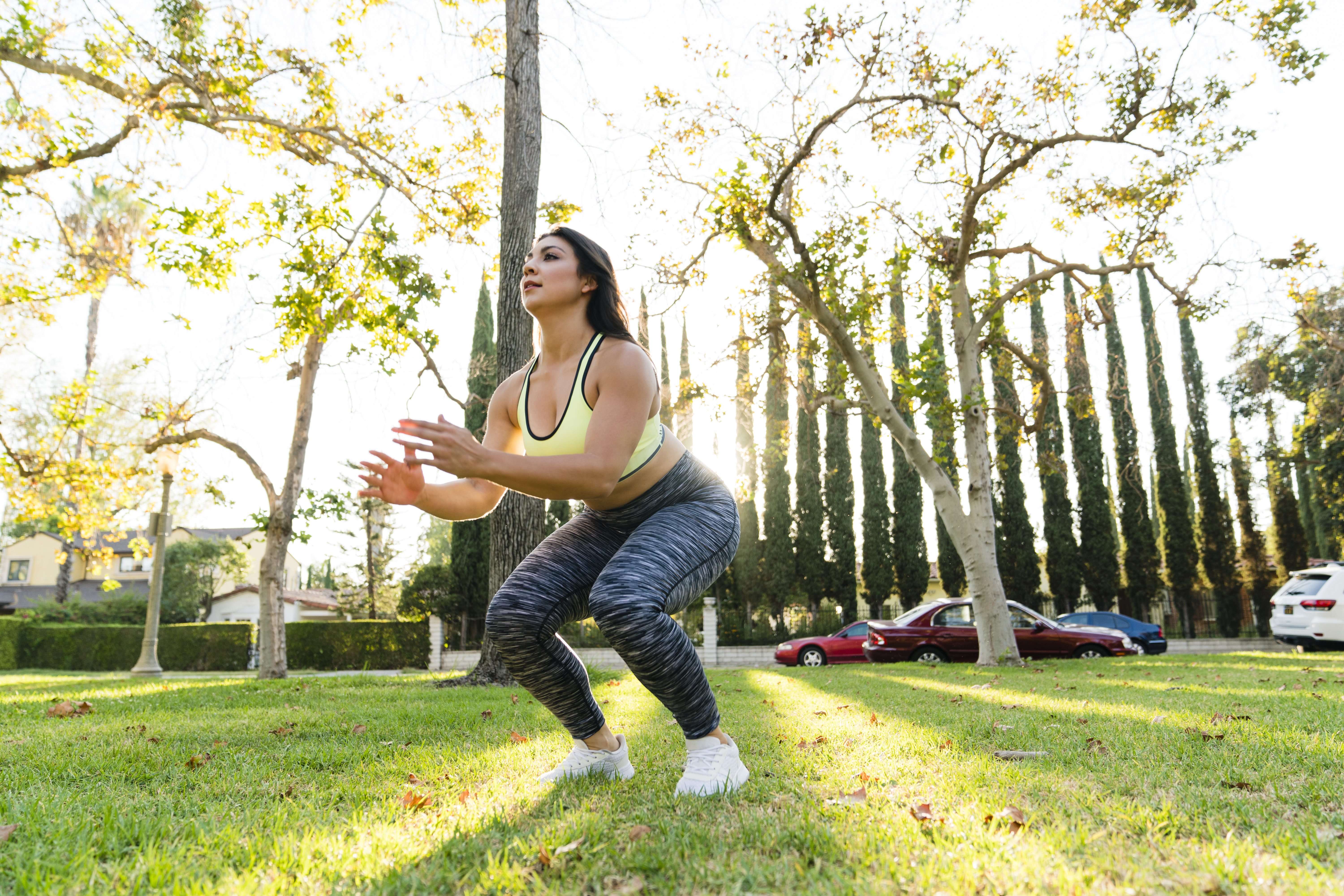 A person is doing a squat exercise outdoors, wearing athletic attire