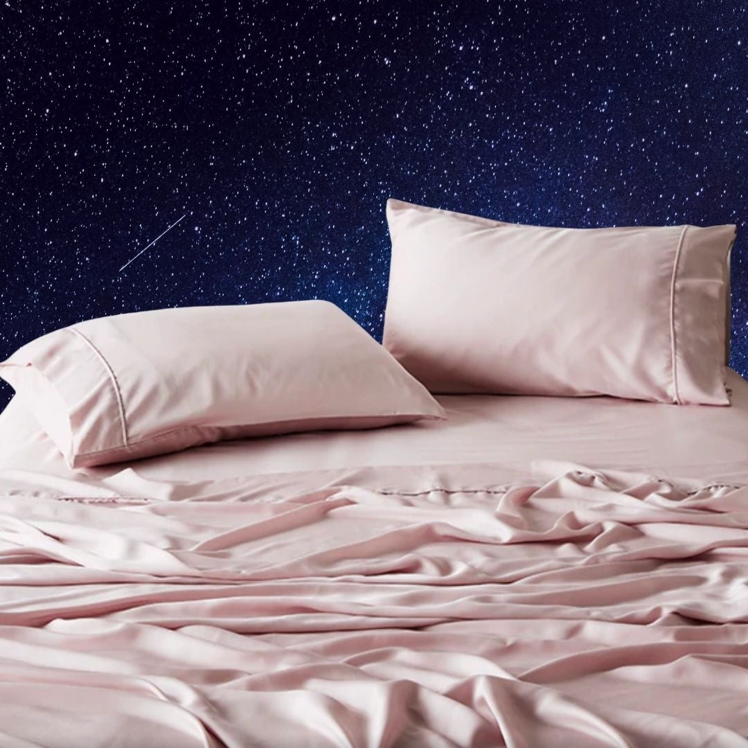 Silk sheets and pillows on a bed, set against a starry night sky backdrop, suggesting luxury and relaxation