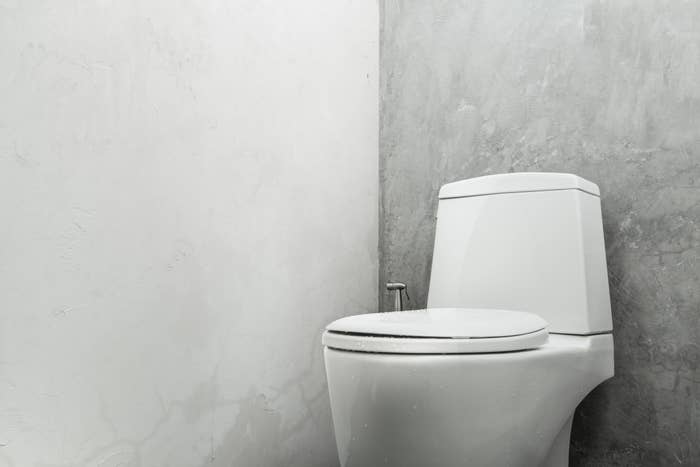 Modern white toilet in a minimalist bathroom with concrete walls