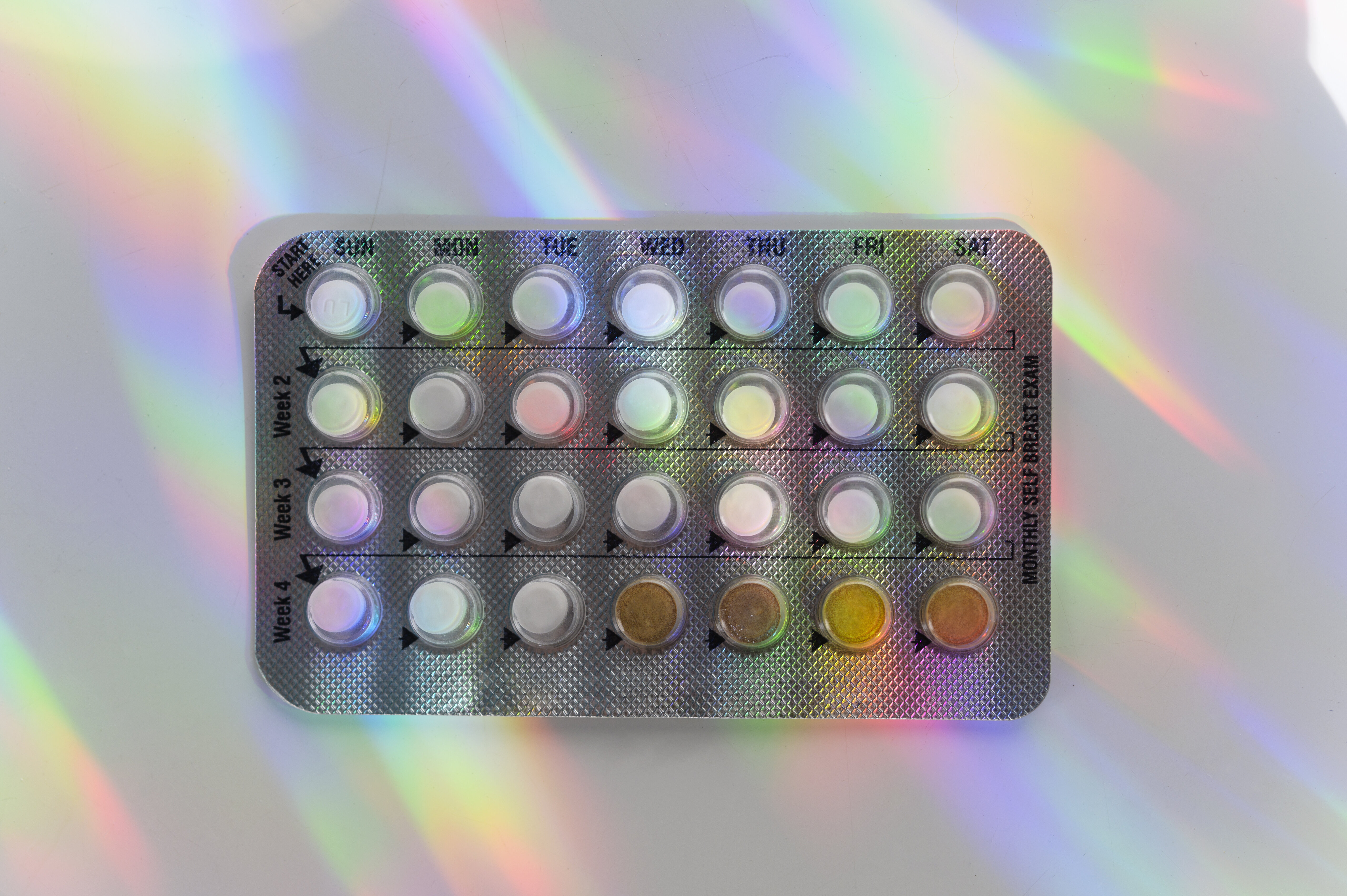 Blister pack of pills with some missing, against a backdrop with light reflections