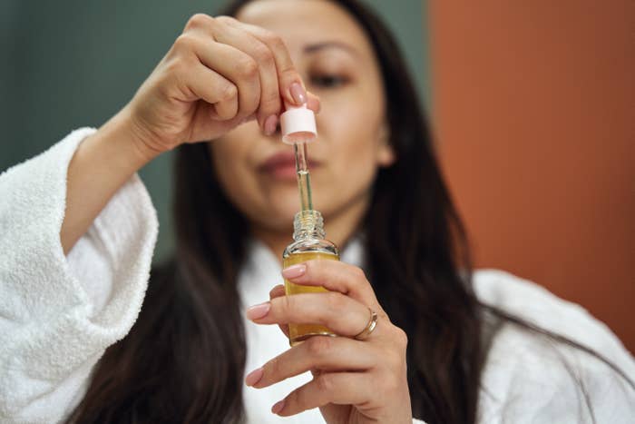 Close-up of a medical professional holding a small glass bottle with an eye dropper