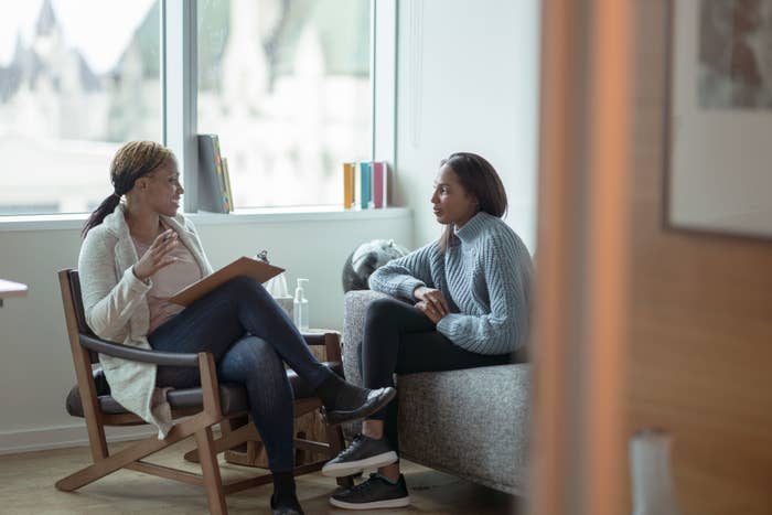 Two people sitting in a counseling session, with one person holding a clipboard and the other listening attentively