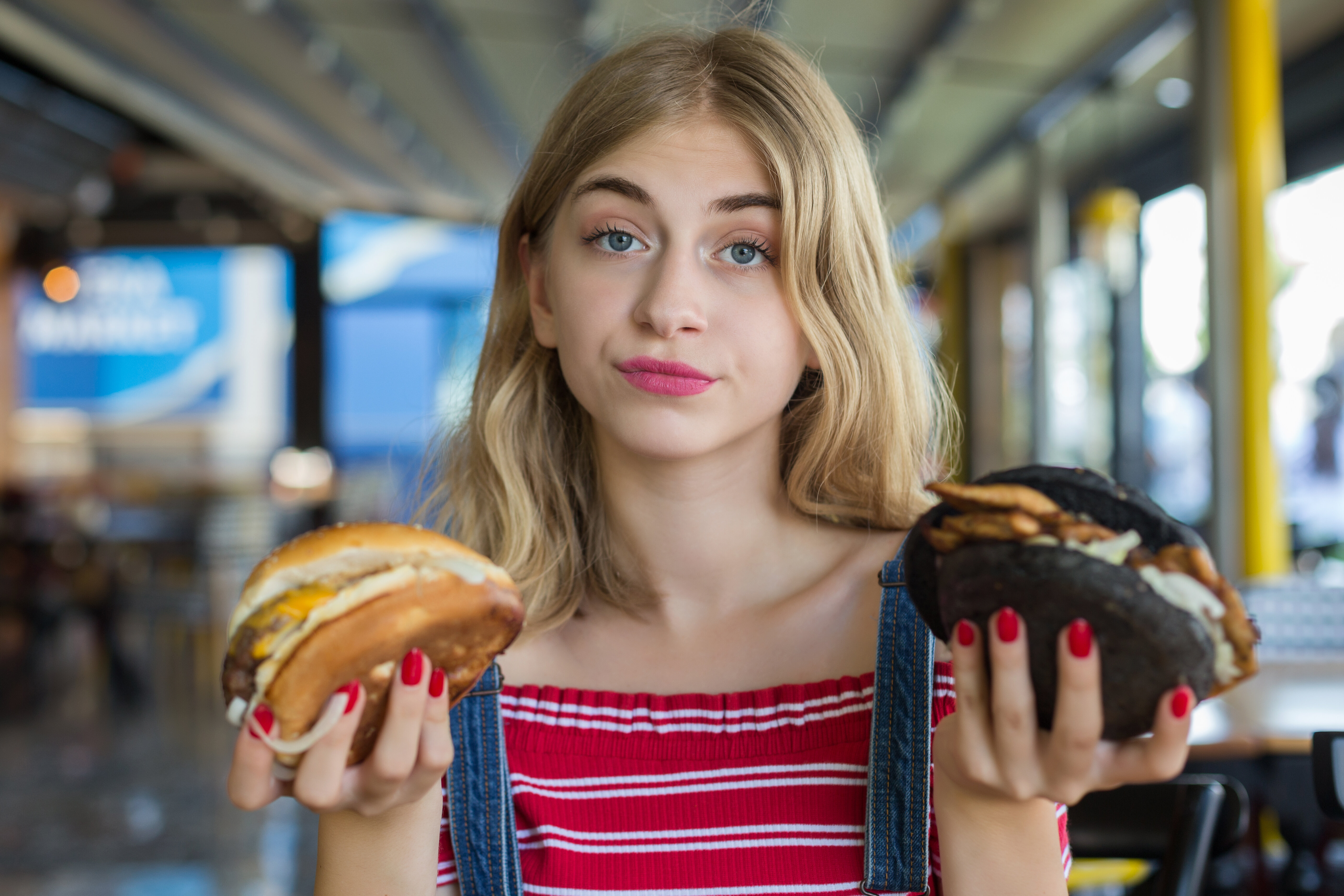 a woman holding two different burgers in each hand