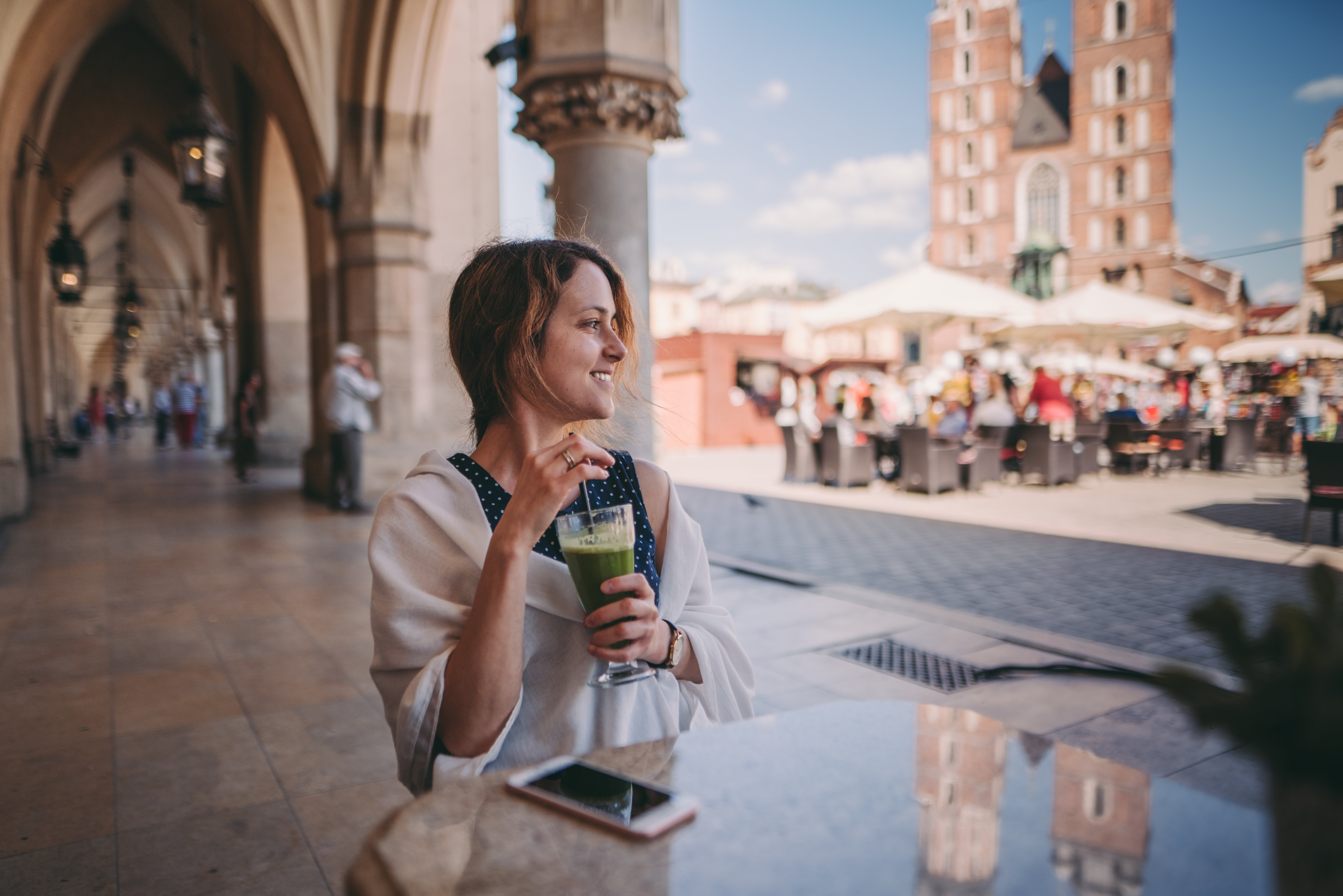 A woman enjoying a drink in the middle of a bustling city