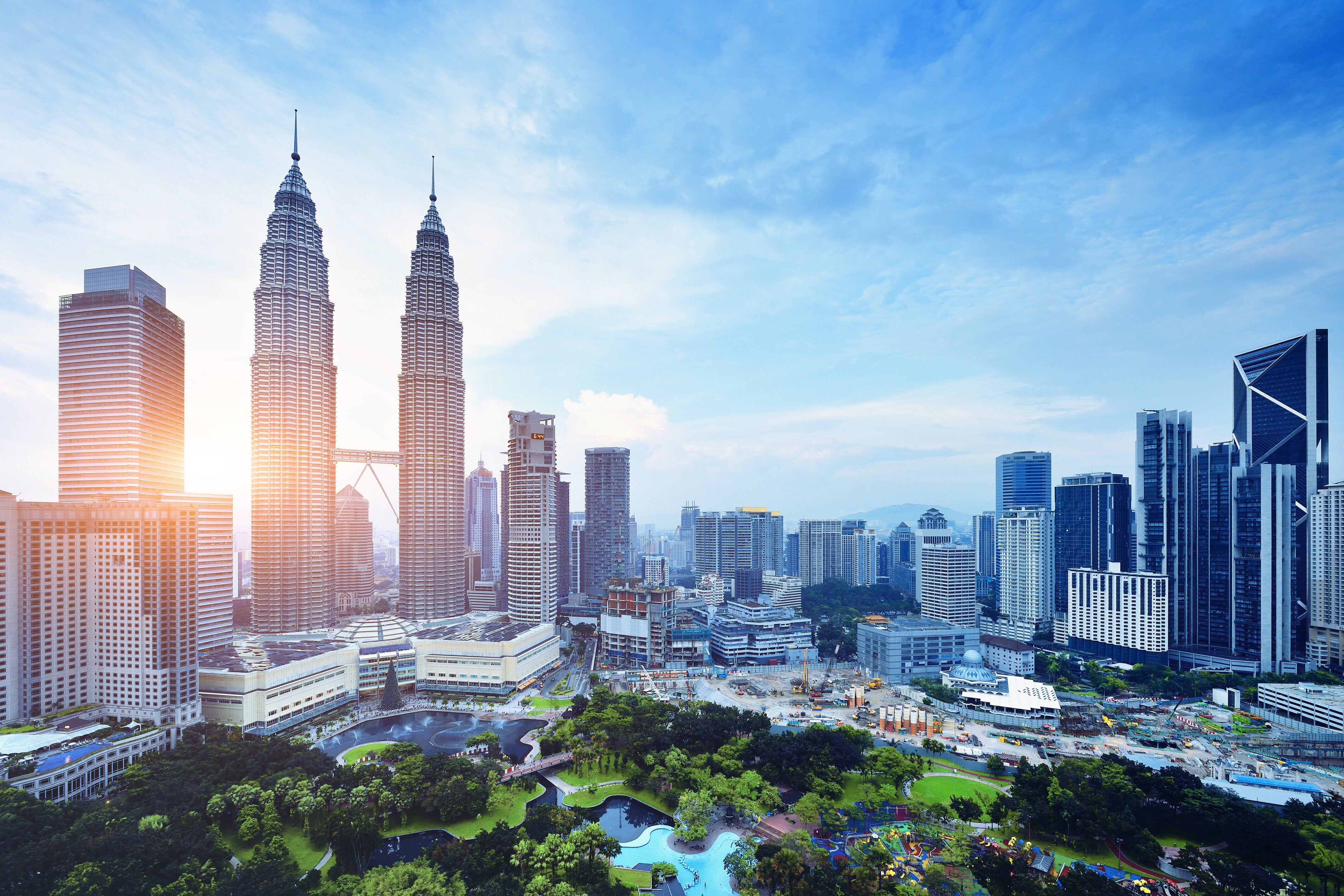 Skyline of Kuala Lumpur featuring the Petronas Twin Towers, with surrounding skyscrapers and a city park in the foreground